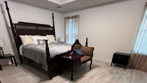 A bedroom with a four-poster bed, a nightstand, a chair, and a small table.