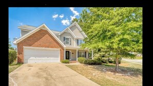 A two-story house with a garage, a front porch, and a tree in the front yard.