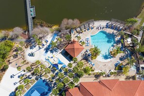 Ein Luftbild eines Resorts mit Swimmingpool, Liegestühlen und Palmen.