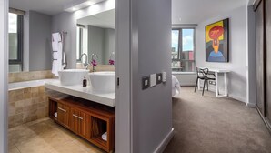 Une salle de bain moderne avec un grand lavabo, un miroir et un meuble en bois. Une petite table et une chaise se trouvent dans la pièce adjacente.