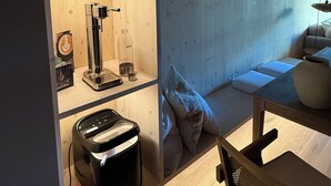 A compact, modern kitchen with wooden cabinetry, a coffee machine, a kettle, and a small dining area with a table and chairs. - The SeeQuartier - A place to arrive, take a deep breath and enjoy Lake Starnberg (Seeshaupt)