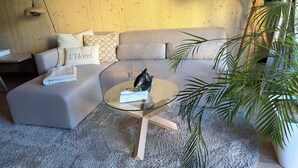 A modern living room with a grey sofa, a glass coffee table, and a potted plant. - The SeeQuartier - A place to arrive, take a deep breath and enjoy Lake Starnberg (Seeshaupt)