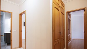 A hallway with wooden doors, a bathroom with a toilet and sink, and a tiled floor. - Modern 3-Bedroom Retreat in. Faro’s City Center (Faro)