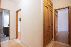 Un corridoio con porte in legno, un bagno con il water e un lavandino, e un pavimento piastrellato.