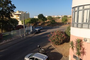 A street view with a parked car, a motorcycle, and a building with large windows.