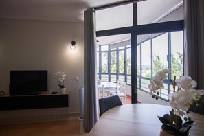 Un soggiorno moderno con televisione a schermo piatto, un'orchidea in vaso e un'area pranzo con tavolo e sedie.