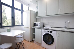 A compact kitchen with a washing machine, a microwave, and a sink.