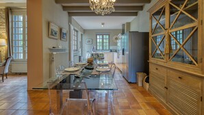 Une cuisine spacieuse avec une table à manger en verre, des armoires en bois et un lustre.
