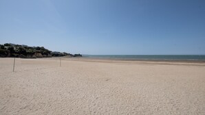 Une vaste plage de sable fin, avec un ciel dégagé et une mer calme.