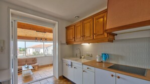A kitchen with wooden cabinets, a sink, and a window overlooking a balcony.