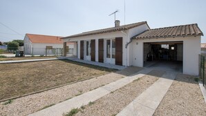 A modern two-story house with a tiled roof, a covered porch, and a gravel driveway.