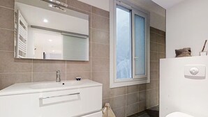 A modern bathroom with a white vanity, a large mirror, and a window. - Charm and comfort in the heart of the historic city (Nice)