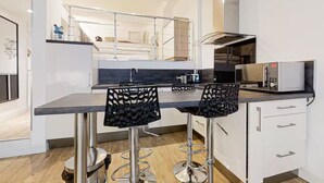 A modern kitchen with a central island, two bar stools, a microwave, and a stainless steel sink. - Charm and comfort in the heart of the historic city (Nice)