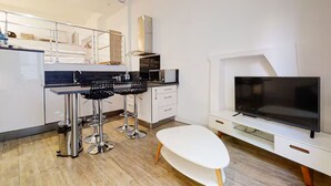 A modern kitchen with a dining area, a TV, and a white table. - Charm and comfort in the heart of the historic city (Nice)
