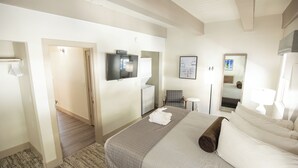 A hotel room with a bed, a television, a chair, a small table, and a mirror. - Tahoe Trail (Stateline)