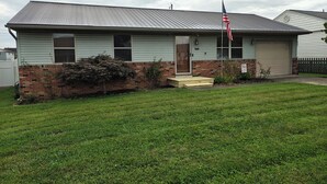 A single-story house with a front porch, a brick foundation, and a metal roof. - Pointer Palace (South Point)