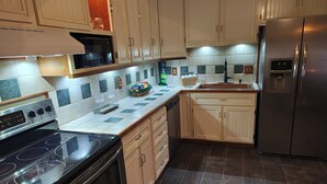 A modern kitchen with a black stove, stainless steel appliances, and light wooden cabinets. - Pointer Palace (South Point)