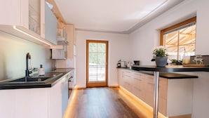 Cozinha moderna com piso de madeira, bancada preta e janela com vista para áreas verdes.