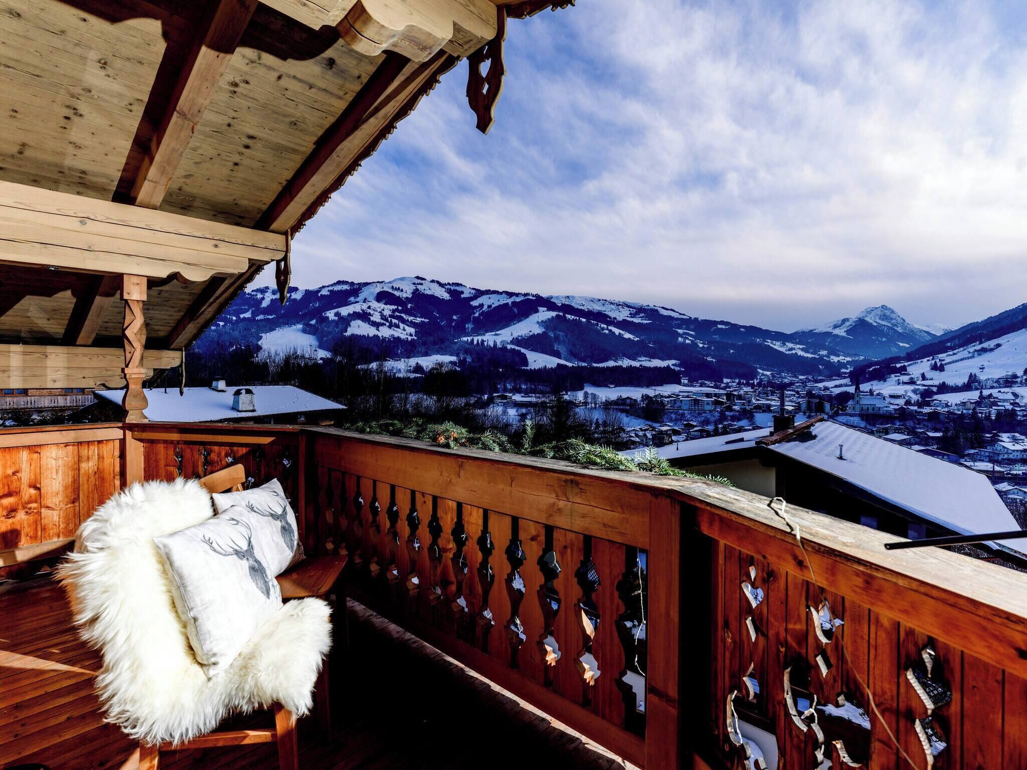 A wooden deck with a view of snow-covered mountains and a town below.