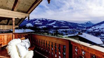 A wooden deck with a view of snow-covered mountains and a town below.