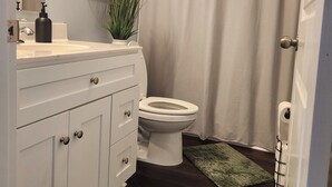 Ein Badezimmer mit weißem Waschtisch, Toilette, Duschvorhang und zwei grünen Teppichen.