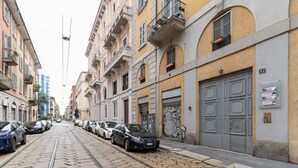 Een straat met tramrails, geparkeerde auto's en gebouwen met balkons en luiken.