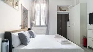 Een slaapkamer met een bed, een kledingkast, een televisie en een radiator.