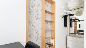 Een kamer met een bureau, een stoel, een kledingkast, een spiegel en een wandplank met boeken.