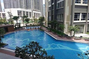 Una piscina rodeada de edificios modernos, con un cielo azul despejado.
