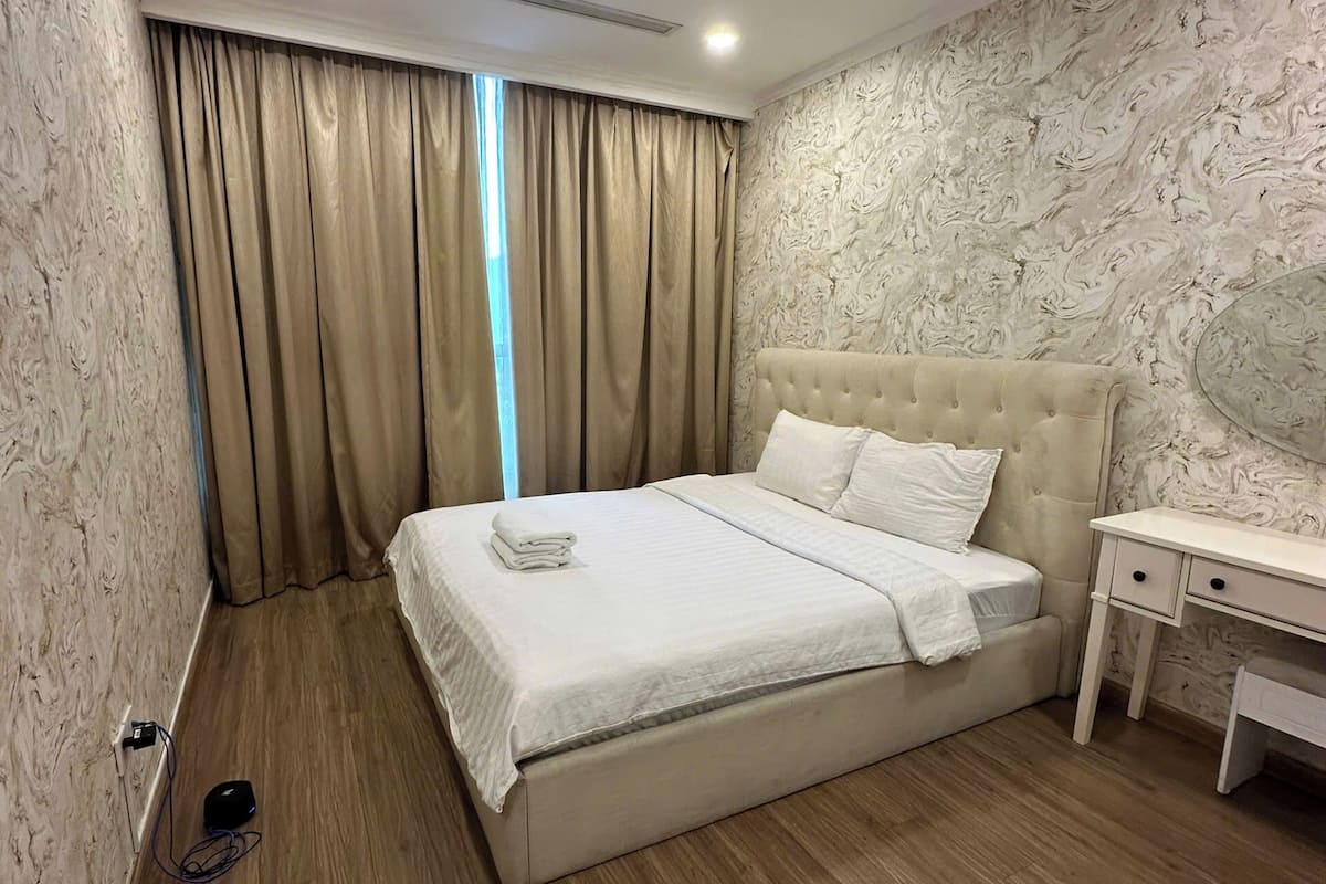 Une chambre à coucher avec un grand lit, une table de chevet et un mur orné d’un motif évoquant le marbre.