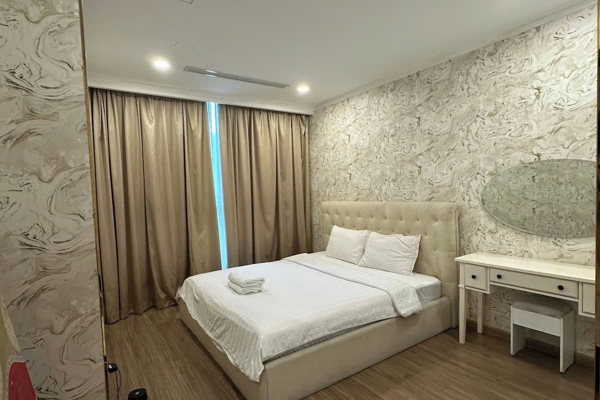 Une chambre avec un grand lit, une table de chevet, un bureau et un climatiseur fixé au mur.