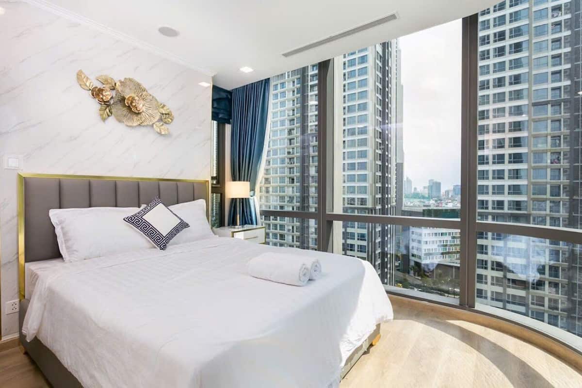 Une chambre d’hôtel moderne dotée d’un grand lit, d’un mur en marbre, d’une vue sur la ville et d’un balcon.