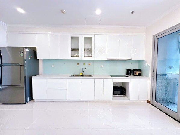 A modern kitchen with white cabinets, a stainless steel refrigerator, a sink, and a microwave. - Landmark 81 - Landmark 81 Plus - VHCT Residences (Ho Chi Minh City)
