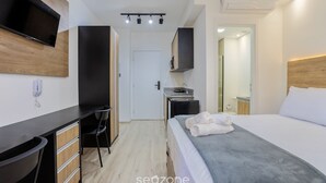 Una habitación de hotel moderna con una cama, un escritorio, una silla, un televisor y un espejo.