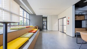 Un interior moderno con una larga zona de asientos tipo banco, un extintor y vistas a través de las ventanas.