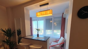 A compact living space with a kitchenette, a dining area, and a seating area with a red chair. - NEW. Take Panorama Studio Apartment: AC, jalouise (Timișoara)