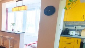 A modern kitchen with yellow cabinets, a clock, and a bar area with stools. - NEW. Take Panorama Studio Apartment: AC, jalouise (Timișoara)