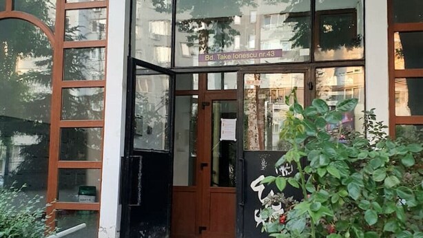 A building entrance with a glass door, a wooden door, and a small garden area with a plant. - NEW. Take Panorama Studio Apartment: AC, jalouise (Timișoara)