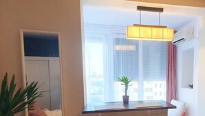 A hotel room with a bed, a window with a view, a mirror, a plant, and a bar area. - NEW. Take Panorama Studio Apartment: AC, jalouise (Timișoara)