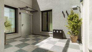 Fachada de un edificio moderno con suelo a cuadros, una puerta, un ventanal y una planta en maceta.