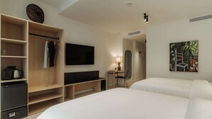Habitación de hotel con cama, televisión, escritorio con silla, armario y un cuadro en la pared.