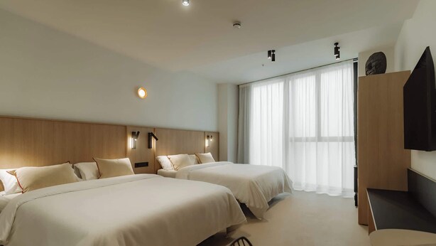Habitación de hotel con dos camas, un escritorio y una televisión.