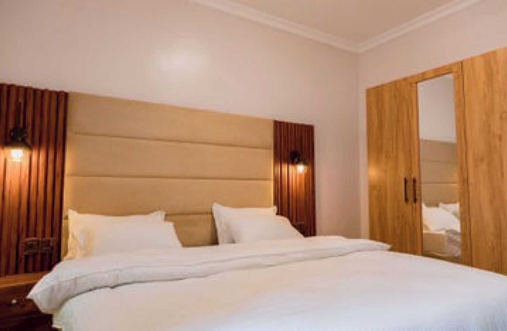 A bedroom with a large bed, wooden headboard, and a wardrobe.