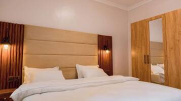 A bedroom with a large bed, wooden headboard, and a wardrobe.