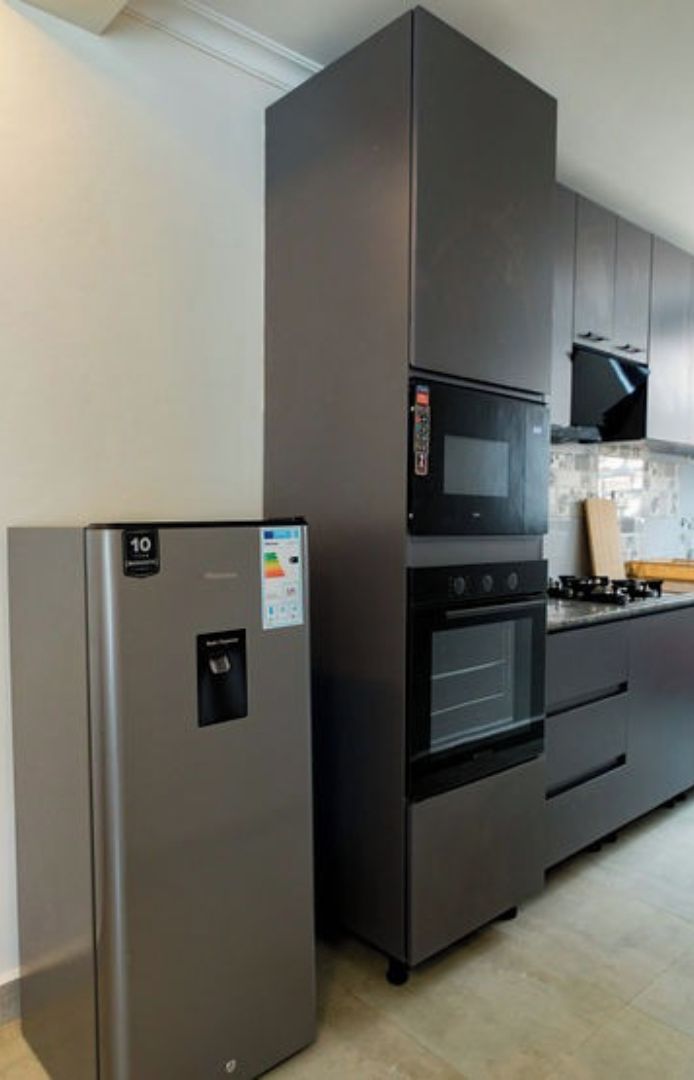 Een keuken met een koelkast van roestvrij staal, een magnetron en een oven.