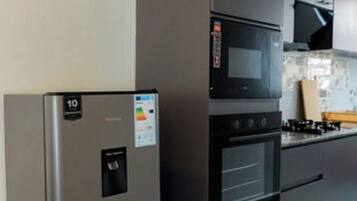 Een keuken met een koelkast van roestvrij staal, een magnetron en een oven.