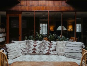 Uma sala de estar acolhedora com sofá, almofadas e uma mesa de madeira.