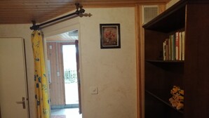 A room with a wooden ceiling, a door, a curtain, a bookshelf, and a small framed picture on the wall. - Le Logis du bChalet Perce-Neige Route de la Cierne 91Les Paccots 1619 (Châtel-Saint-Denis)