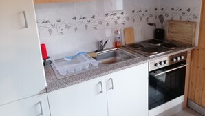 A kitchen with white cabinets, a granite countertop, a stainless steel sink, a stove, and an oven. - Le Logis du bChalet Perce-Neige Route de la Cierne 91Les Paccots 1619 (Châtel-Saint-Denis)