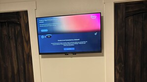 Ein Flachbildfernseher an einer weißen Wand, der einen Anmeldebildschirm für Amazon Fire TV anzeigt.